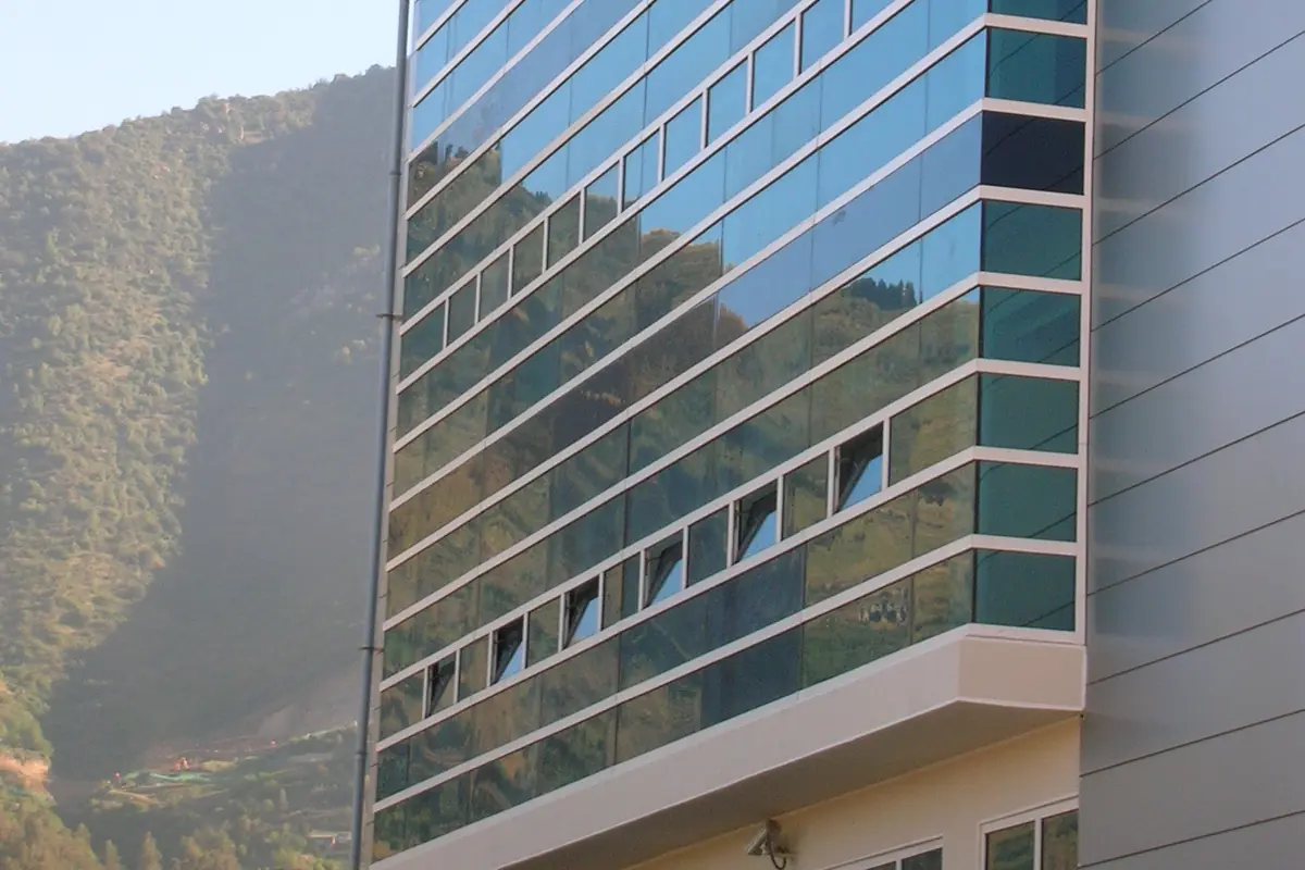Glass-fronted tower block against a green hillside