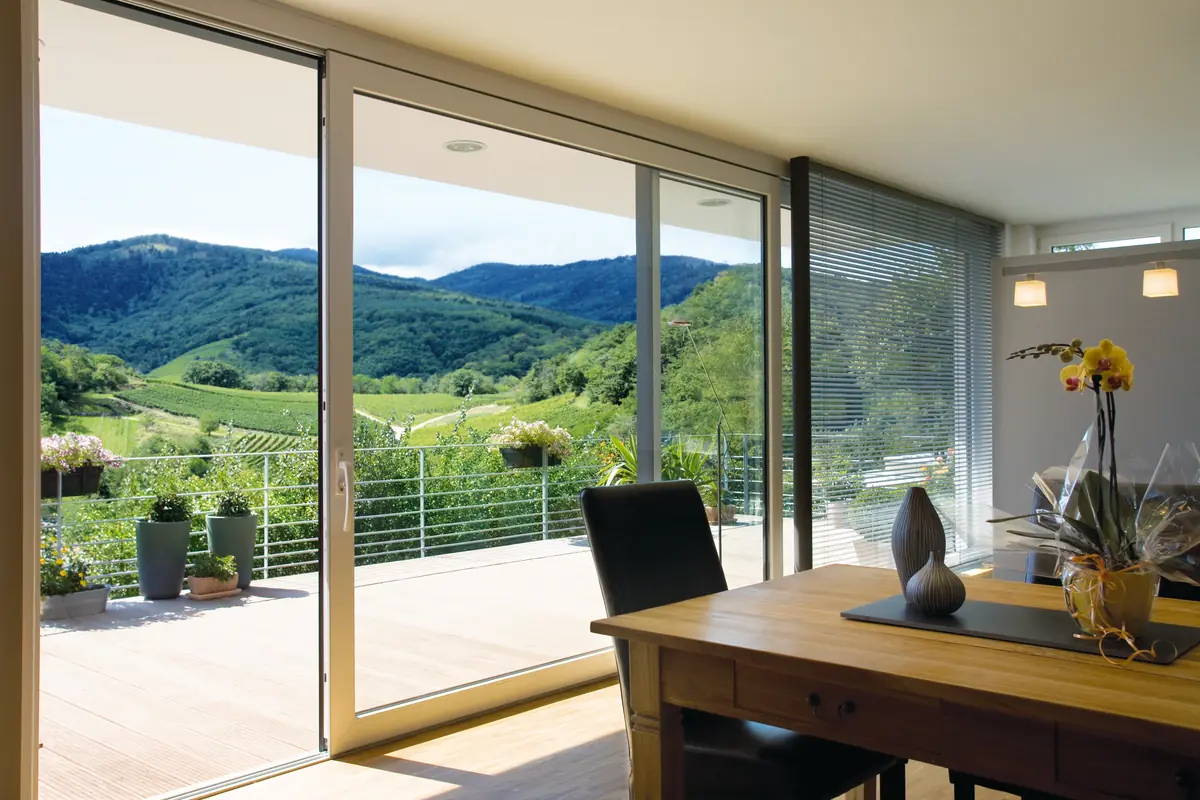 Large sliding window opening onto a terrace with a view of green hills