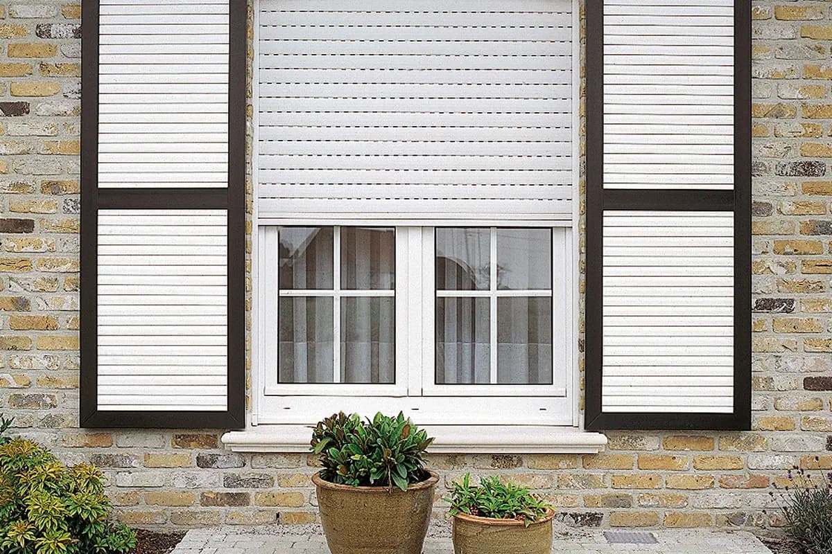 White window with an external roller shutter and louvred side shutters