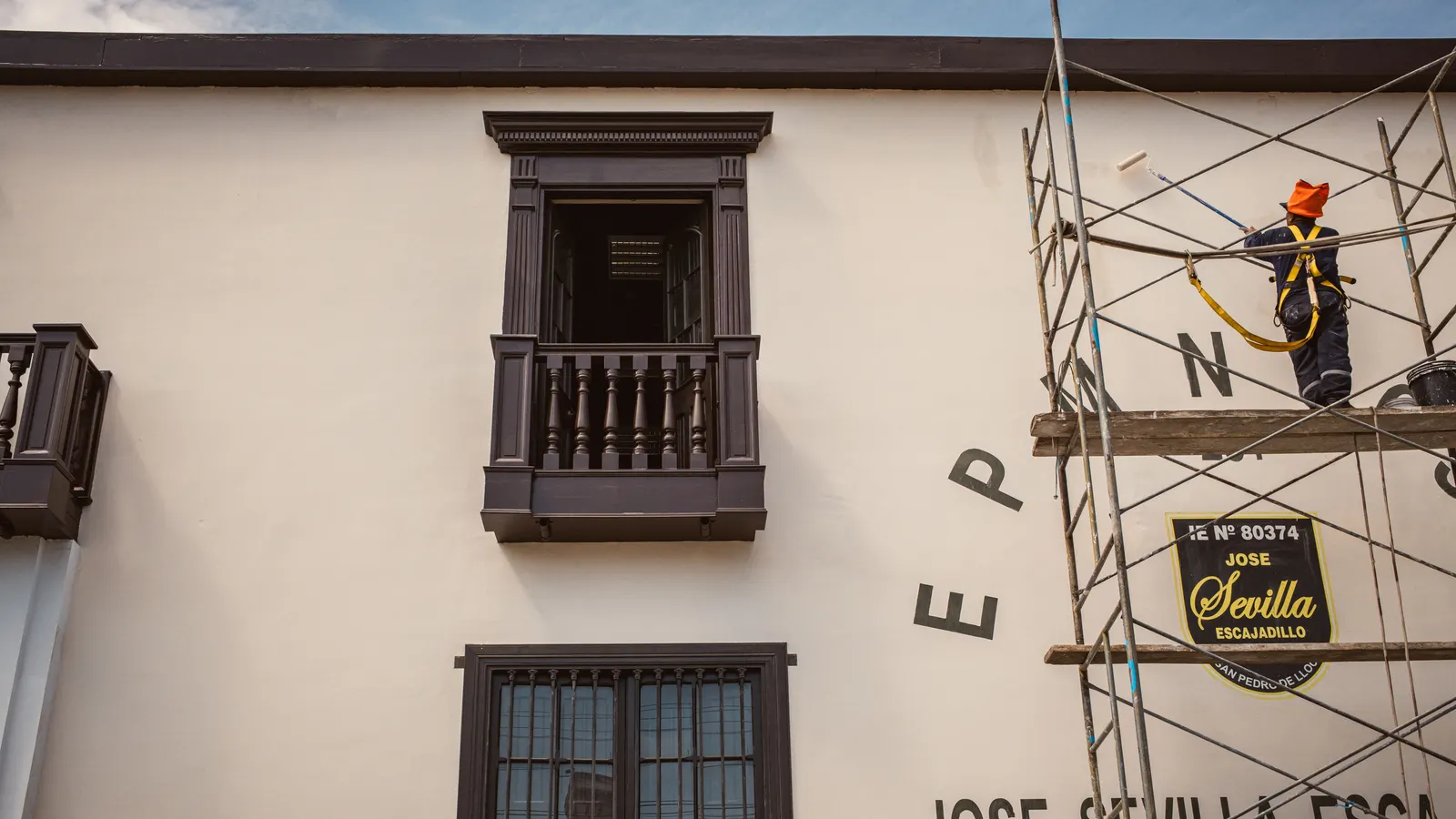 Operario trabajando sobre un andamio montado en la fachada de un edificio de viviendas, con los huecos de ventana a la vista