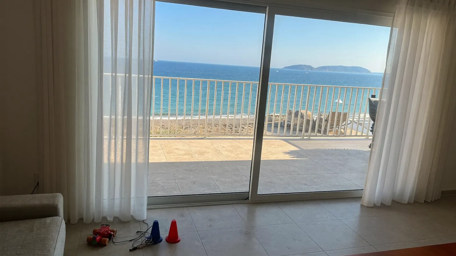 Puerta balconera corredera de suelo a techo que da a una terraza con vistas al mar