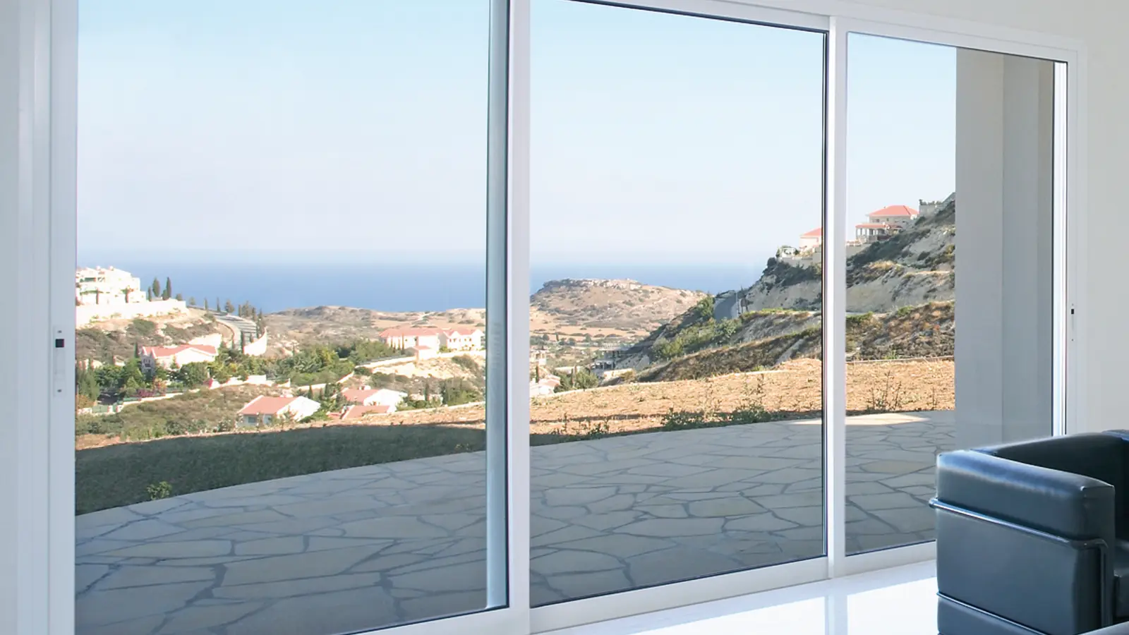 Gran hueco acristalado de suelo a techo visto desde dentro de una vivienda, con la luz del exterior entrando por él