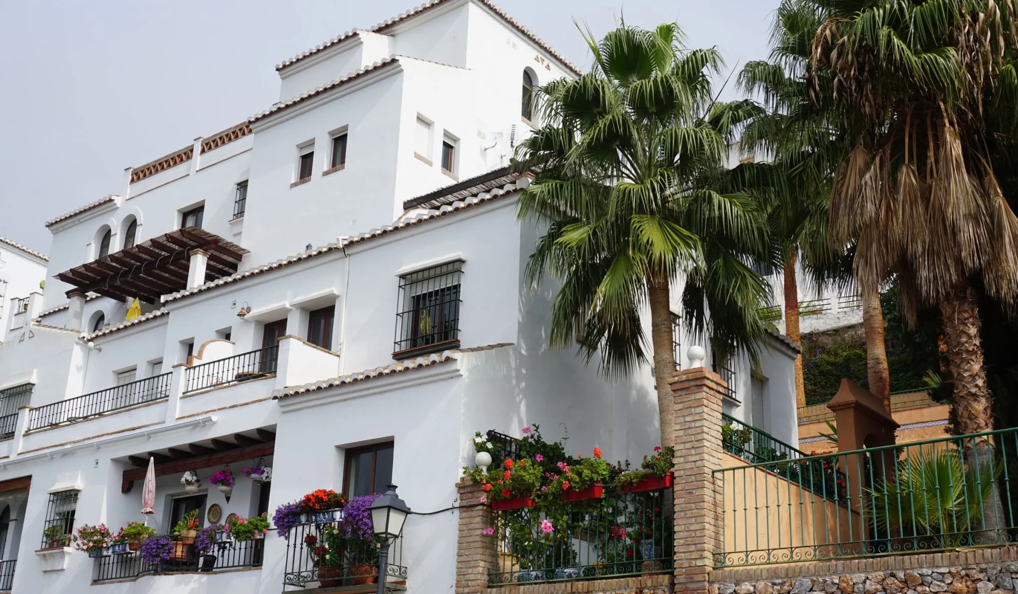 Whitewashed Mediterranean house with palm trees and balconies